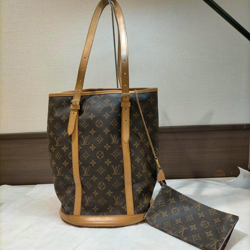 Louis Vuitton Monogram Bucket GM bag with attached monogram pouch shown on a flat surface.