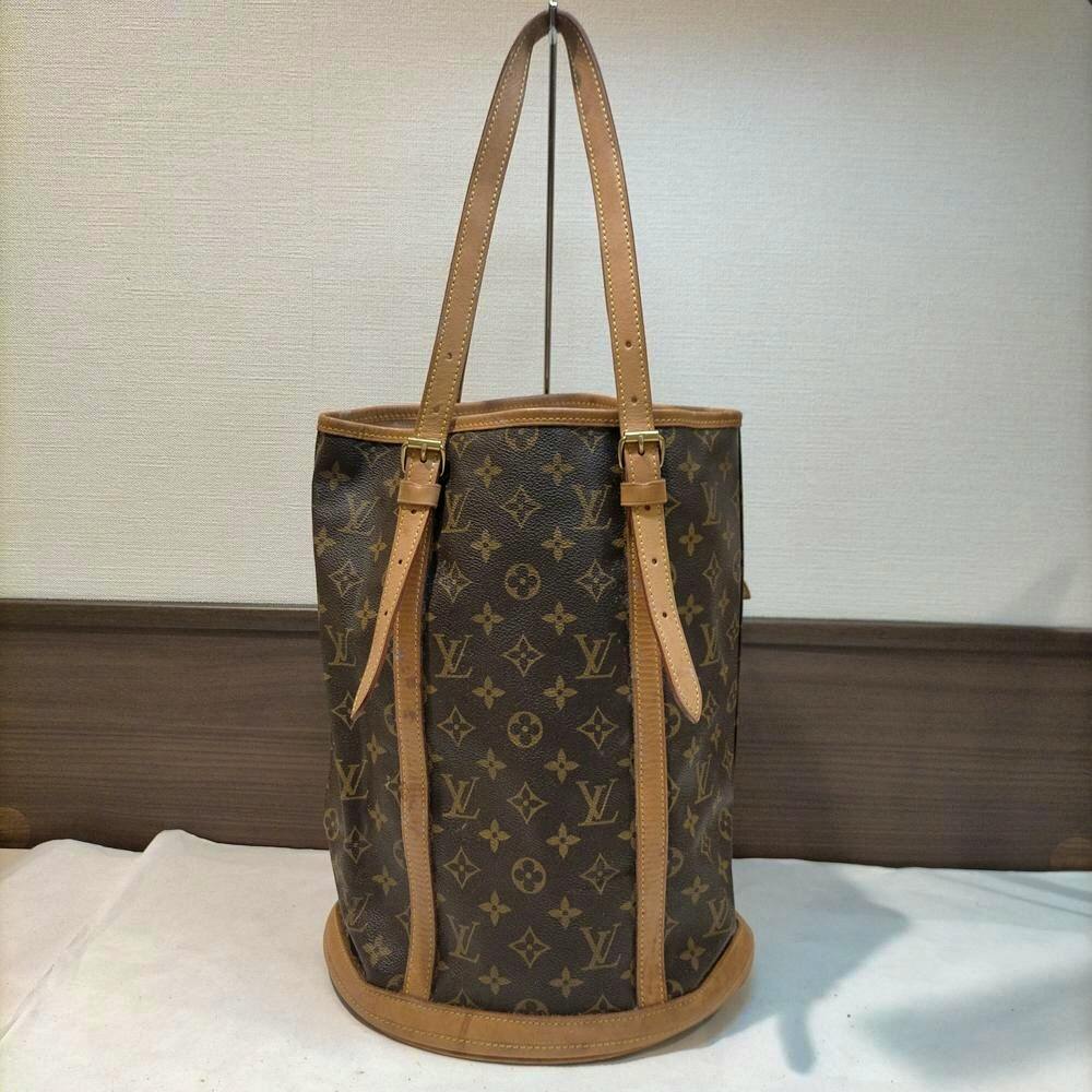 Front view of a Louis Vuitton monogram Bucket PM tote bag with leather trim and shoulder straps.