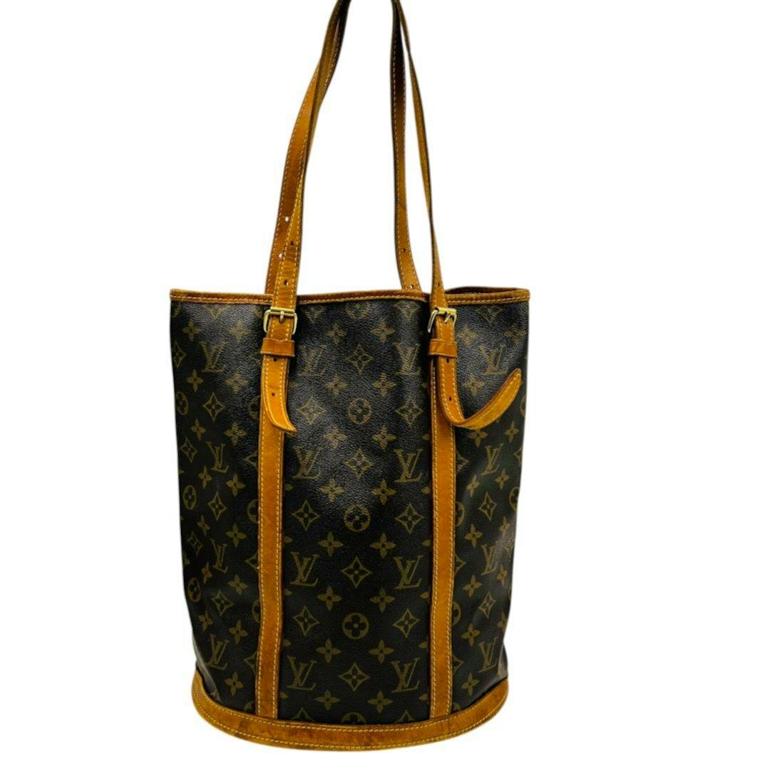 Front view of a Louis Vuitton monogram bucket shoulder bag with brown leather trim and long shoulder straps.