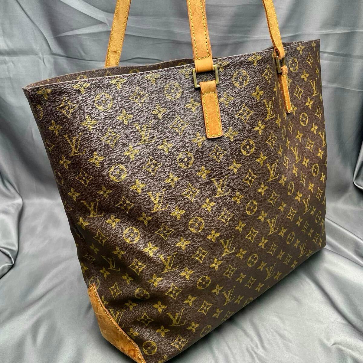 Louis Vuitton monogram tote bag in brown coated canvas with leather handles, shown at an angle.