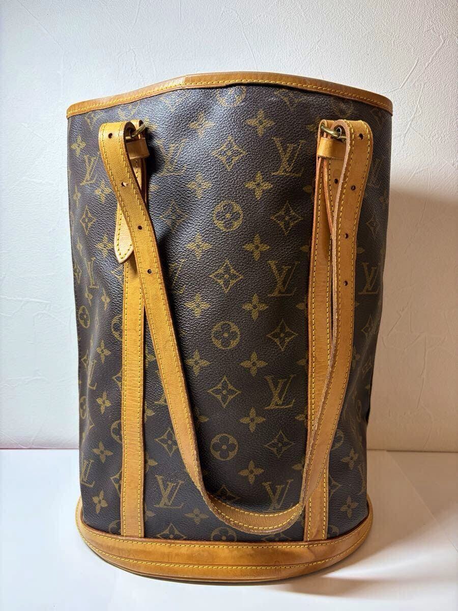 Louis Vuitton monogram canvas Bucket GM bag with tan leather straps and trim shown upright against a white background.