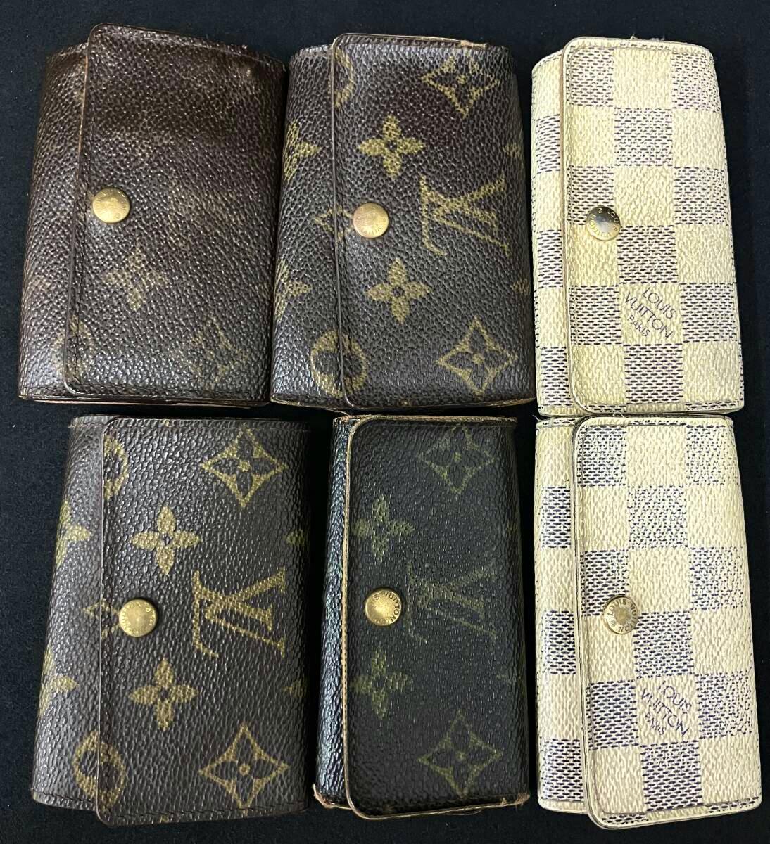 Six Louis Vuitton canvas key cases (monogram and Damier Azur patterns) arranged on a dark background.