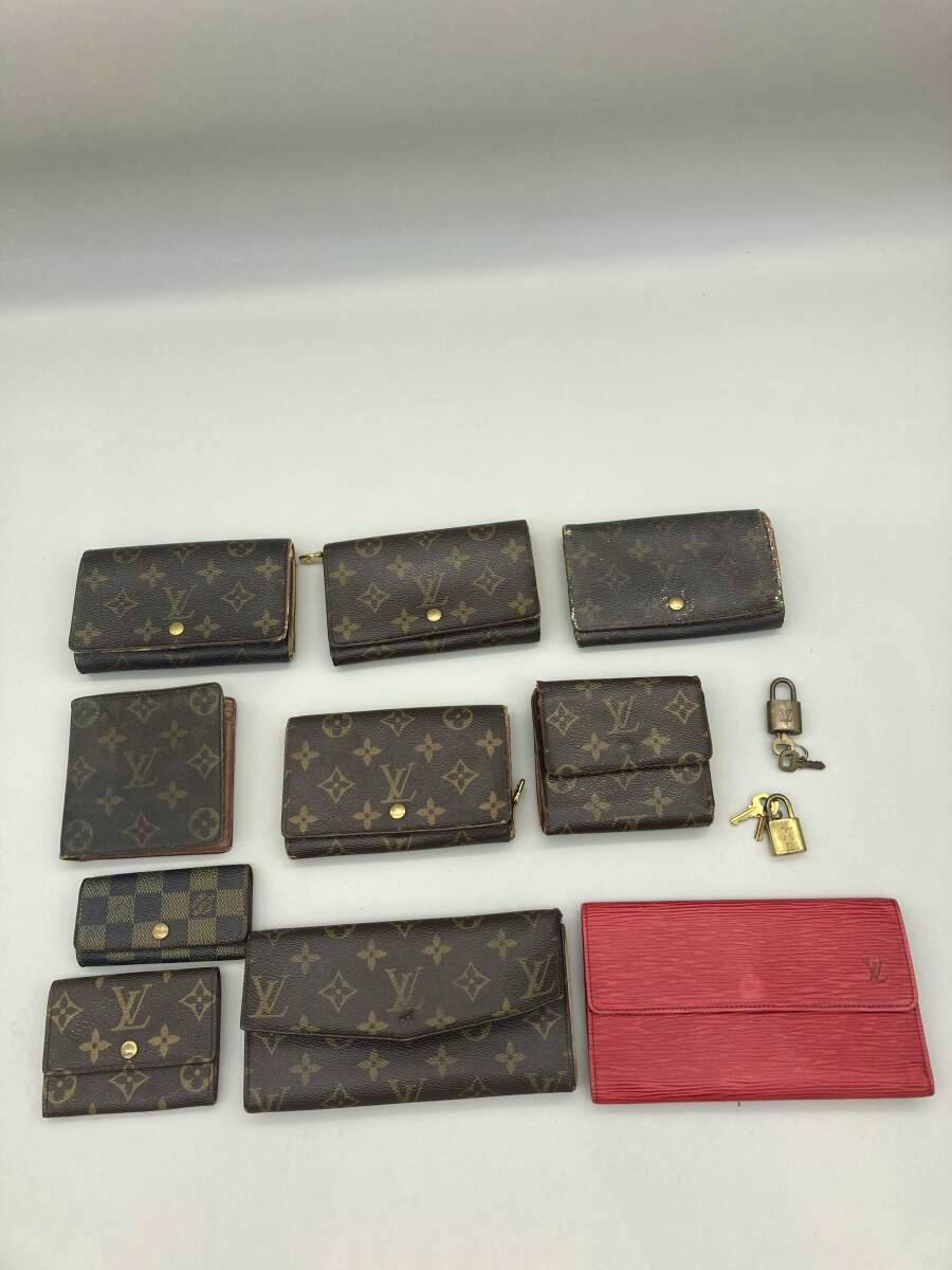 Multiple Louis Vuitton wallets (monogram, Damier, Epi) and two small padlocks arranged on a white background.