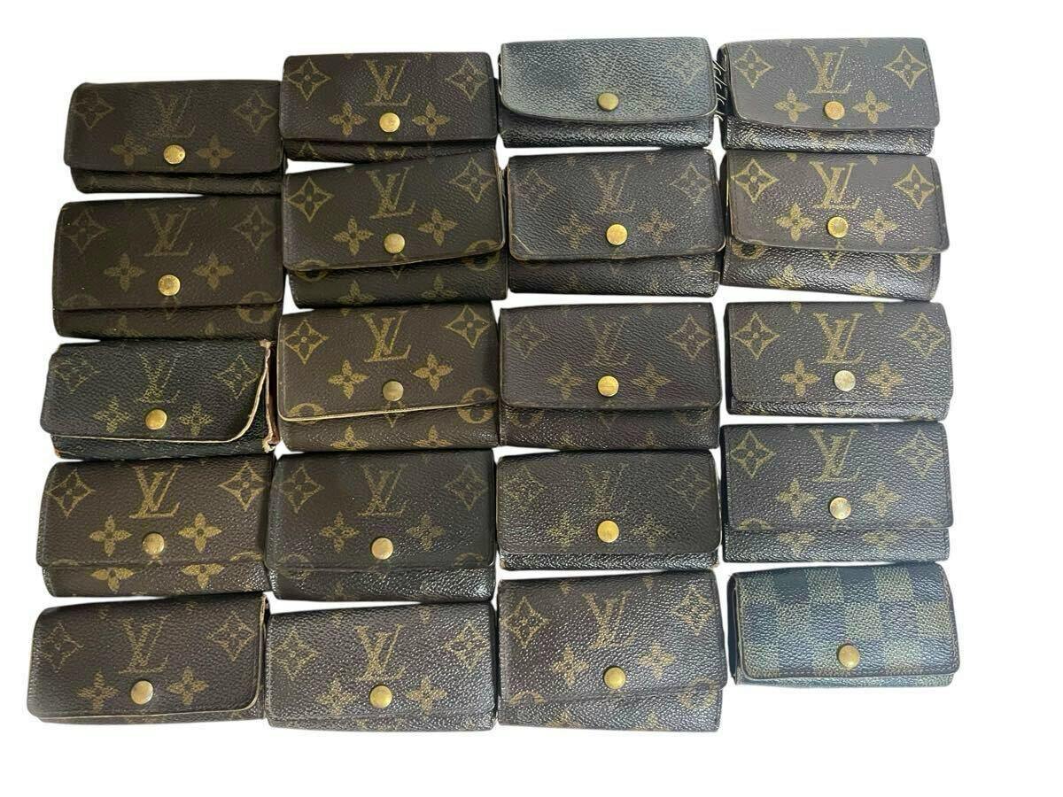 Twenty Louis Vuitton monogram and Damier leather key cases arranged in rows on a white background.