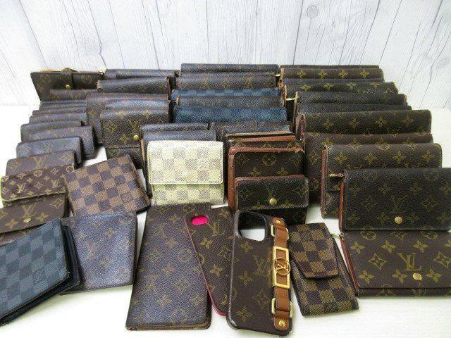 Many Louis Vuitton monogram and Damier wallets, key cases, and a phone case arranged on a white surface.