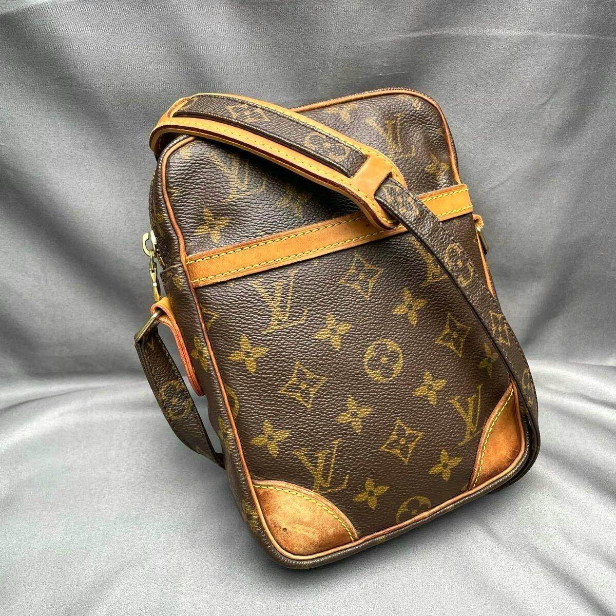 Louis Vuitton monogram Danube shoulder bag in brown canvas with leather trim and strap shown on a gray background.