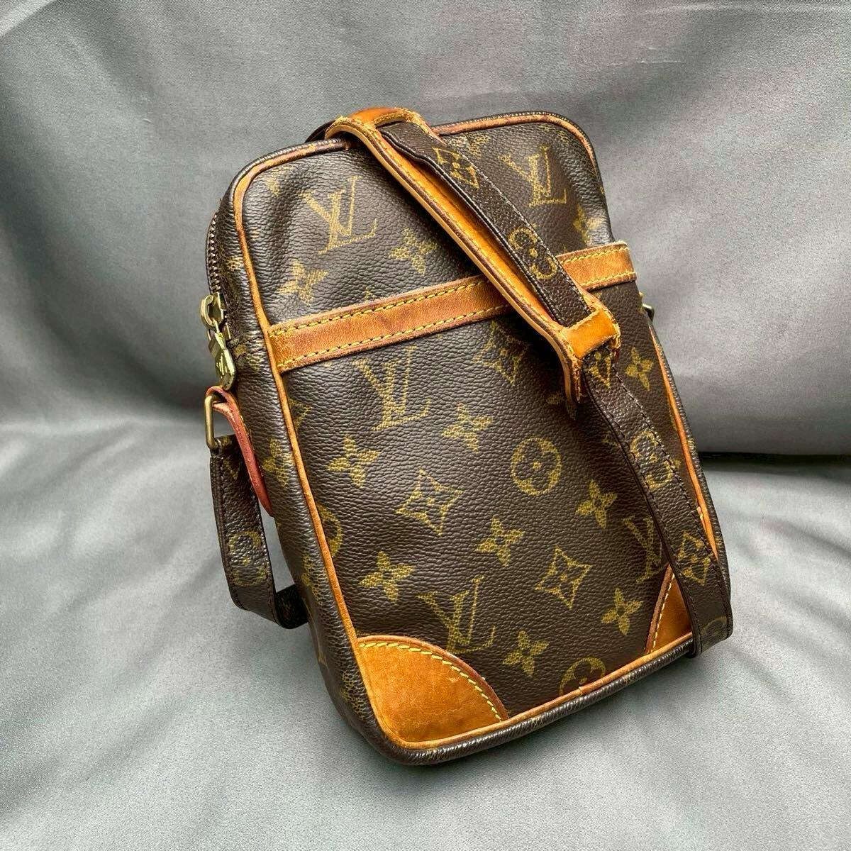 Louis Vuitton monogram Danube shoulder bag in brown canvas with leather trim and an adjustable shoulder strap on a gray background.