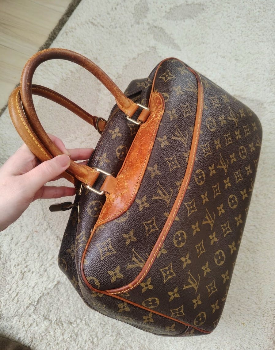 Angled photo of the Louis Vuitton Monogram canvas handbag (ドーヴィル ボストンバッグ) showing the monogram canvas, leather handles, and leather piping.
