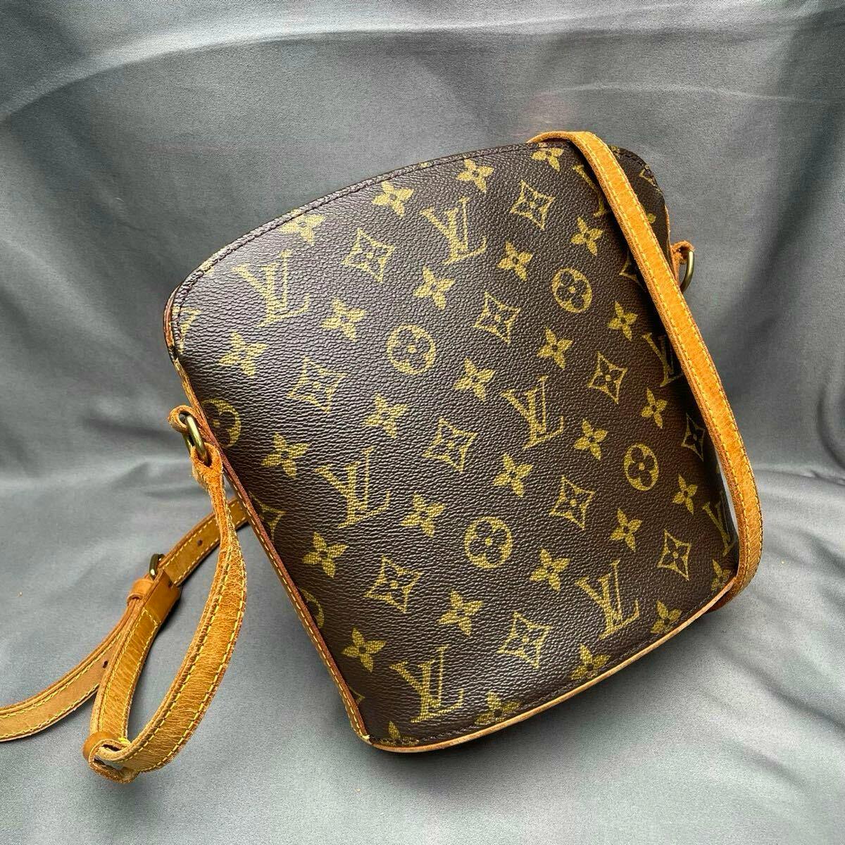 Louis Vuitton monogram canvas shoulder bag with leather strap photographed on a gray background.