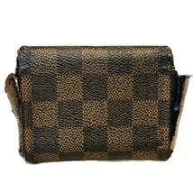 Small Damier-pattern Louis Vuitton coin purse showing wear and scuffed edges.