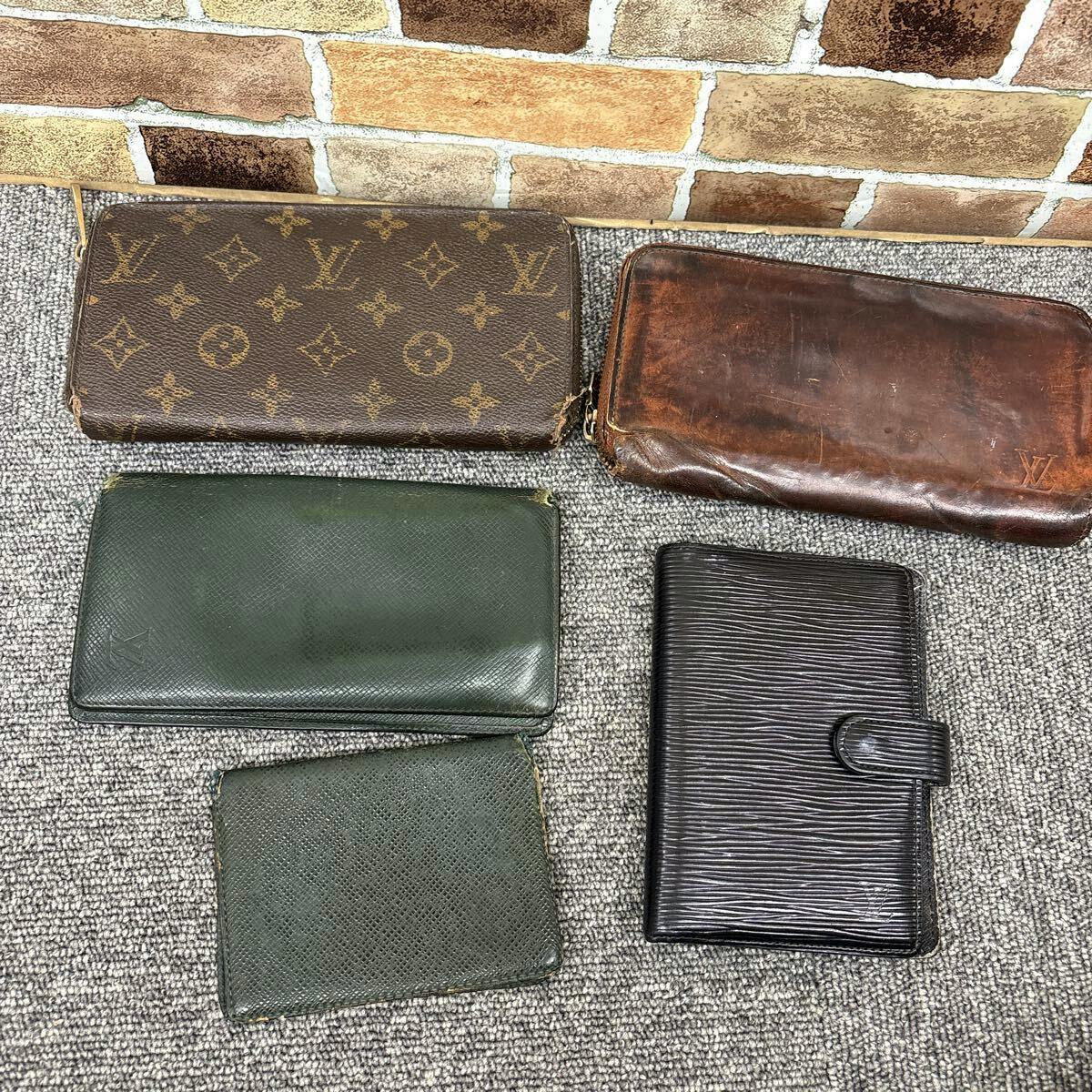 Five Louis Vuitton wallets and small accessories, including monogram and Epi styles, arranged on a carpeted floor.