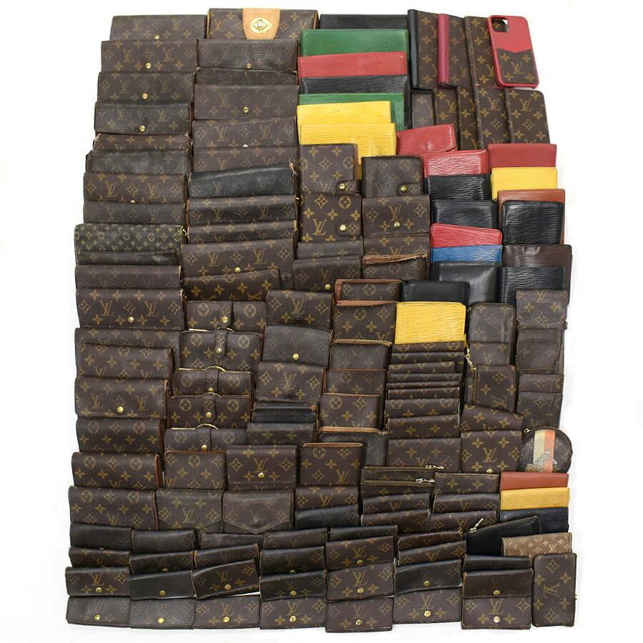 A large assortment of Louis Vuitton monogram and colored leather wallets, key cases, and small cases arranged on a white background.