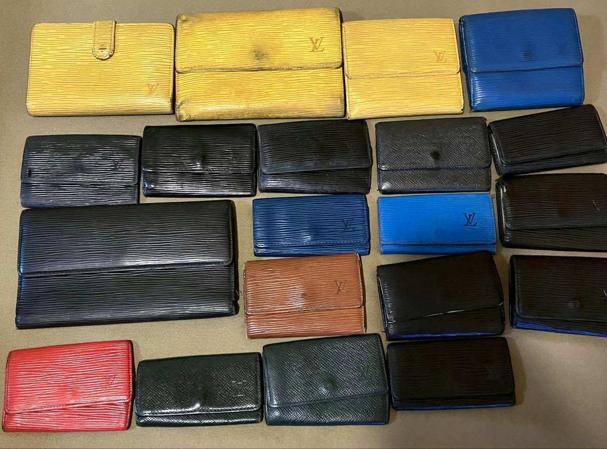 Multiple Louis Vuitton wallets and small leather goods in various colors and conditions laid out on a flat surface.
