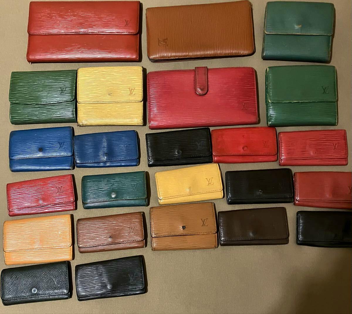 A laid-out assortment of Louis Vuitton Epi leather wallets and small cases in various colors on a flat surface.
