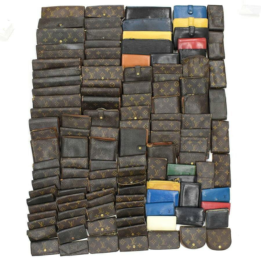Top-down photo of about 120 Louis Vuitton wallets and small leather goods in monogram and Epi canvas arranged on a white background.
