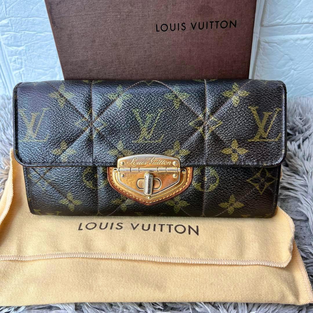 Front view of a Louis Vuitton monogram long wallet (cow leather) with a gold-tone clasp displayed on a Louis Vuitton dust bag and box.