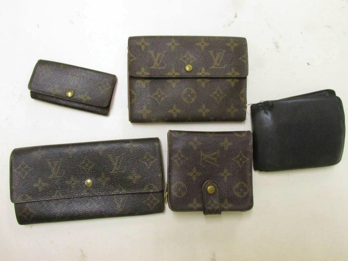 Five Louis Vuitton wallets and cases, mainly monogram canvas with one black leather piece, arranged on a white surface.