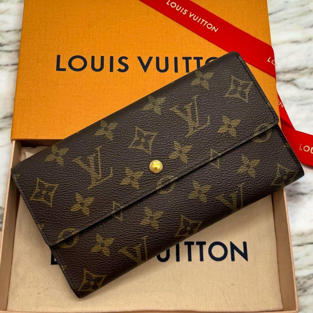 Louis Vuitton monogram fold wallet placed in its box on a dust bag.