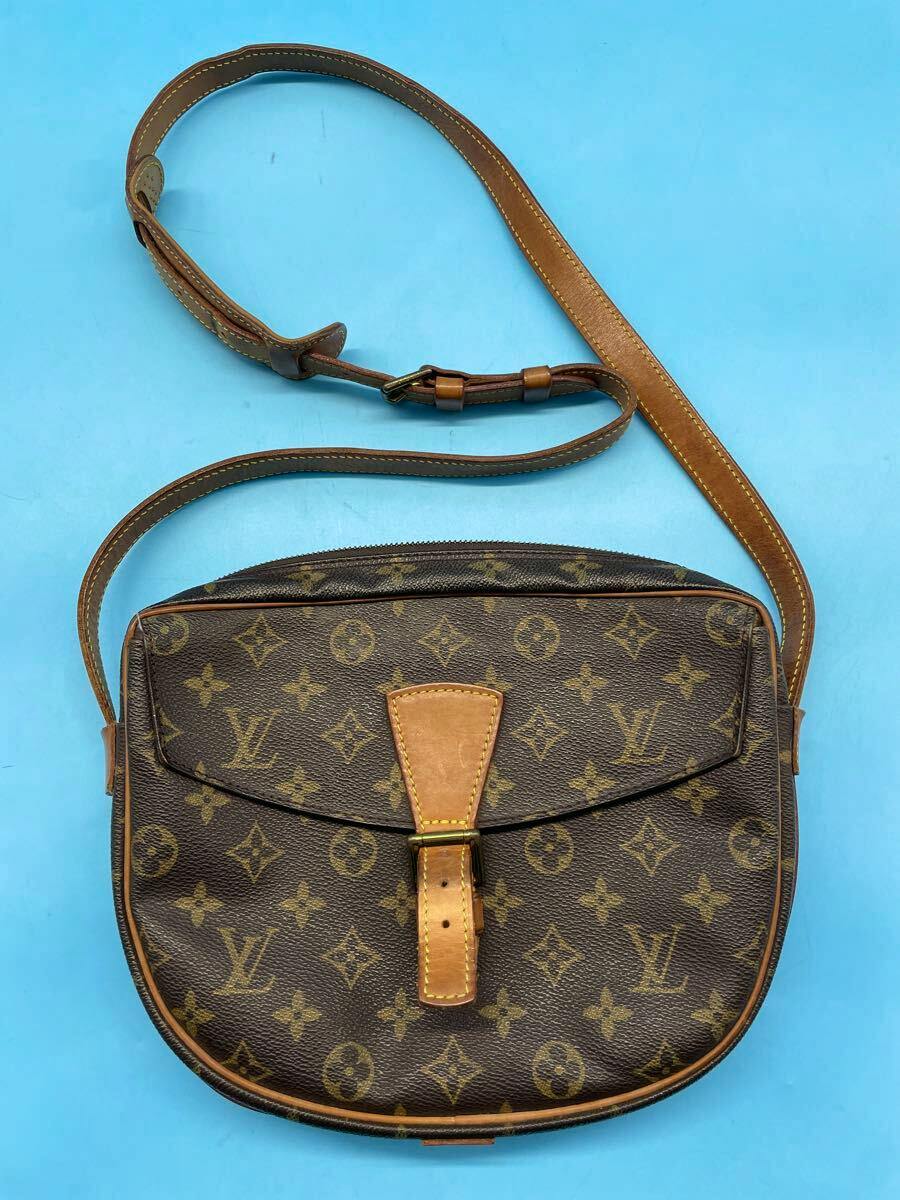 Front view of a Louis Vuitton monogram canvas shoulder bag with flap and buckle, shown with its leather strap on a blue background.