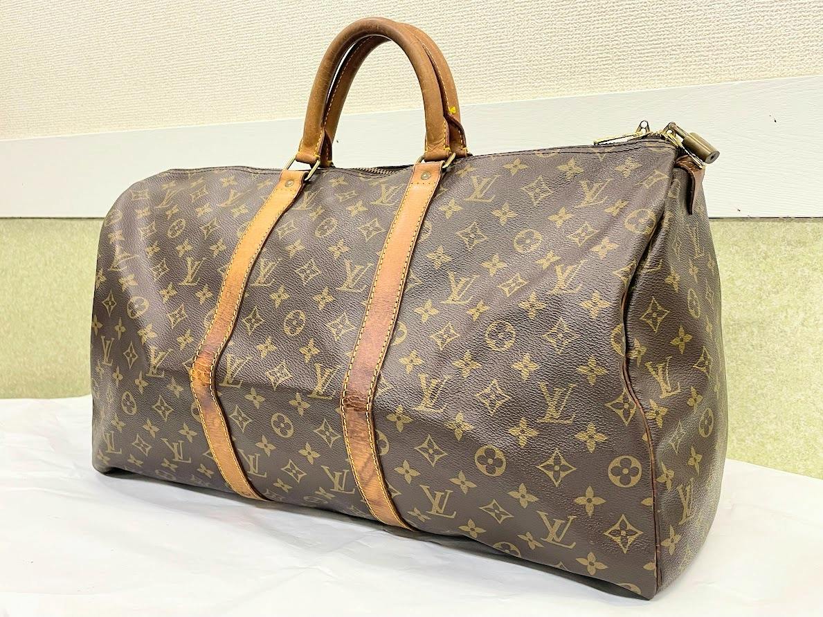 Louis Vuitton monogram duffel bag (M41426) with leather handles and straps displayed on a flat surface.