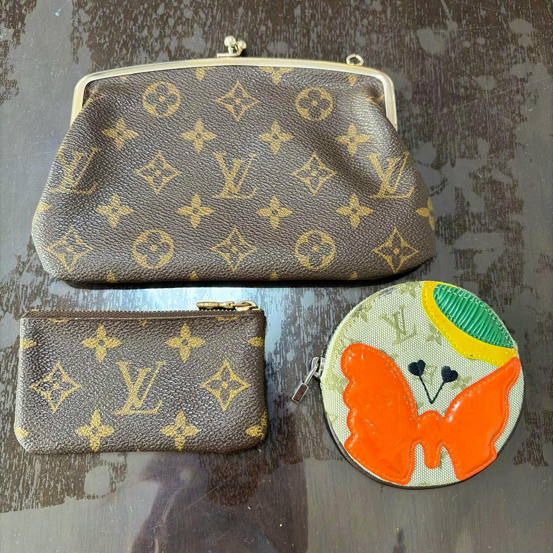 Louis Vuitton monogram clasp pouch on a dark surface, shown with a small monogram zip pouch and a round butterfly coin purse.