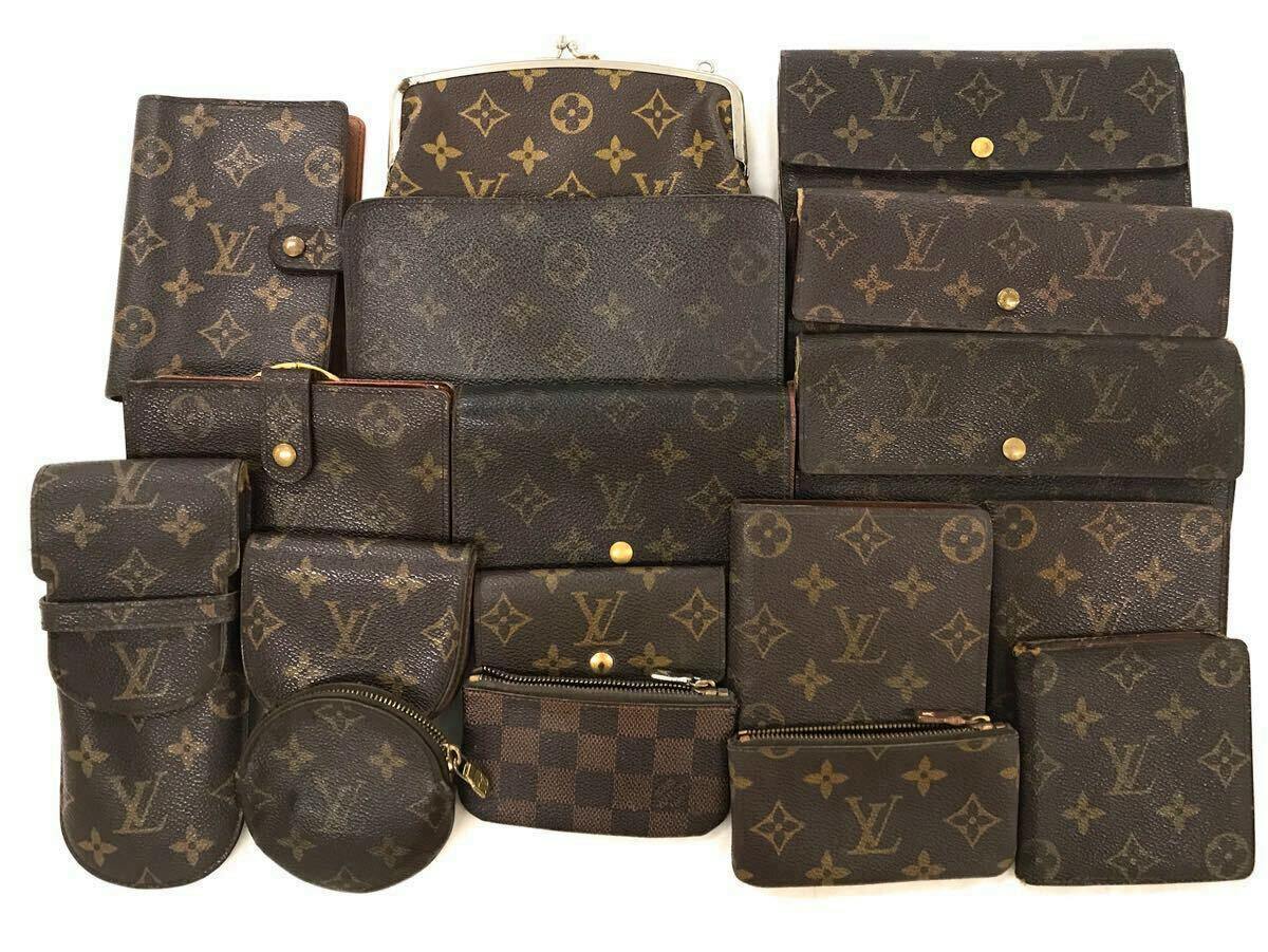 Seventeen Louis Vuitton monogram wallets and small leather goods arranged together on a white background.