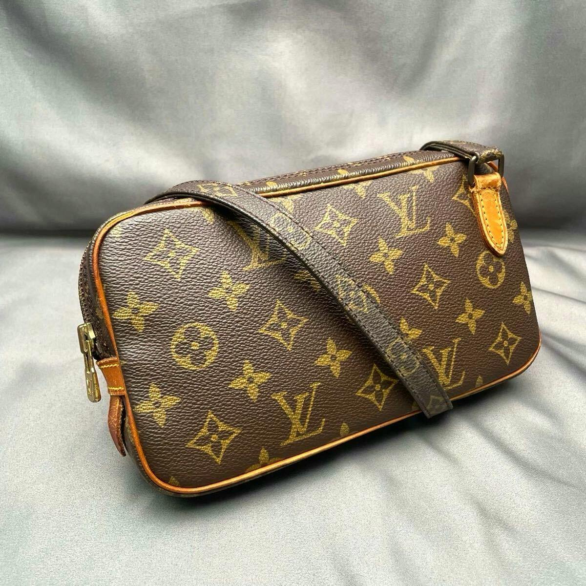 Angled view of a Louis Vuitton monogram Marly Bandoulière shoulder bag with strap on a gray fabric background.