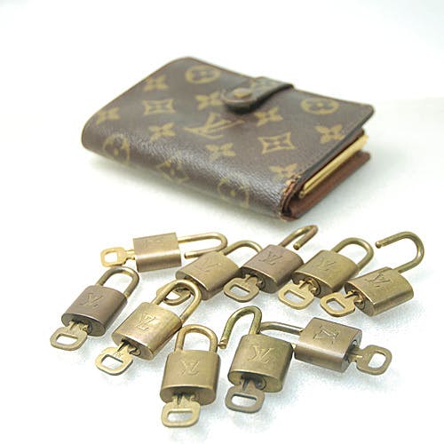 Multiple Louis Vuitton padlocks displayed in front of a monogram wallet.