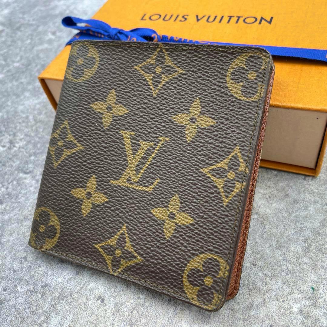 Folded Louis Vuitton monogram canvas wallet (Portefeuille) shown angled on a surface with its box visible behind it.