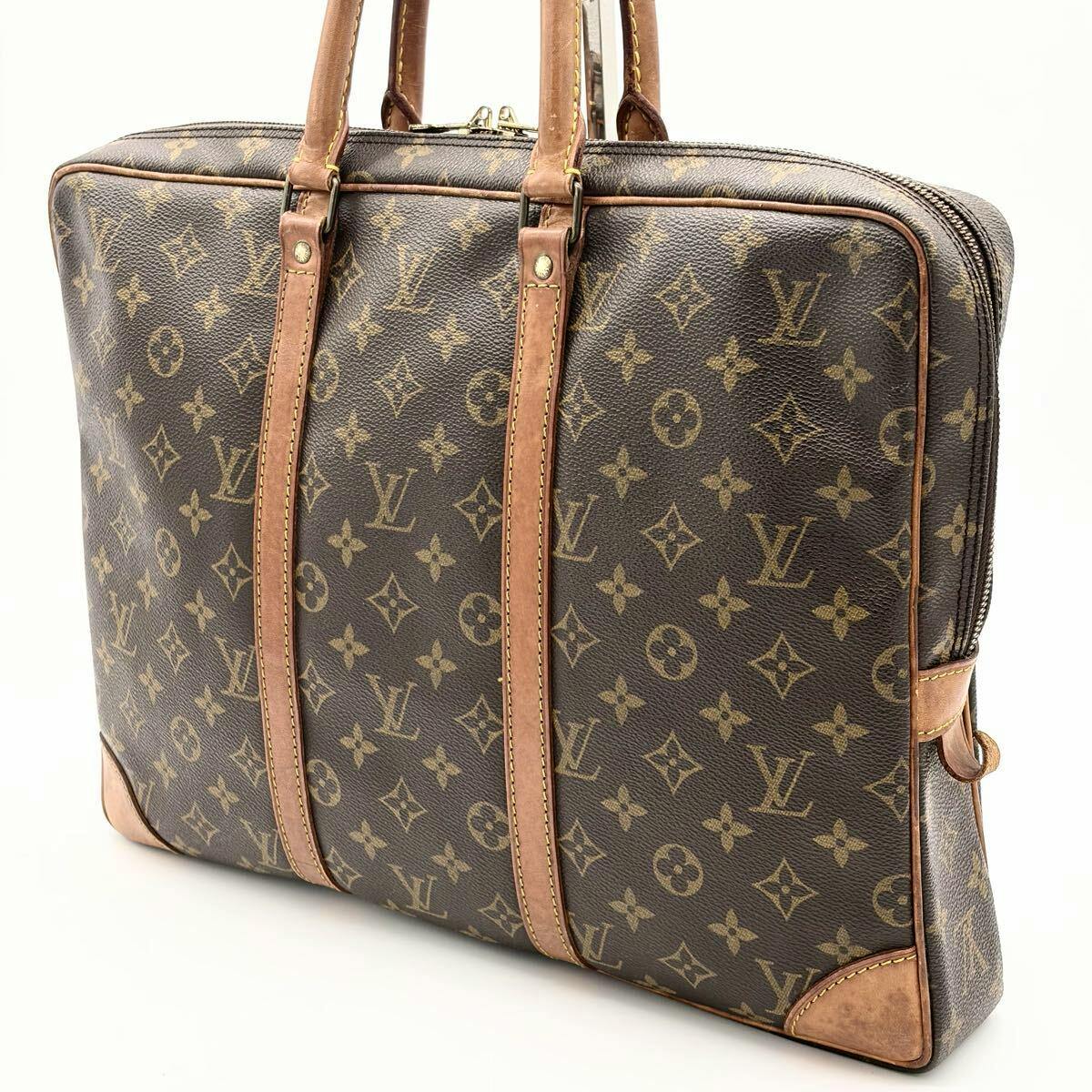 Angled front view of a Louis Vuitton monogram briefcase with leather trim and handles visible.