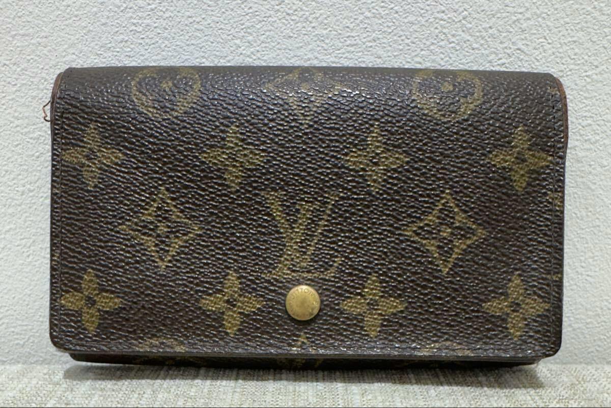 Front exterior of the Louis Vuitton monogram canvas wallet showing a round snap button closure.