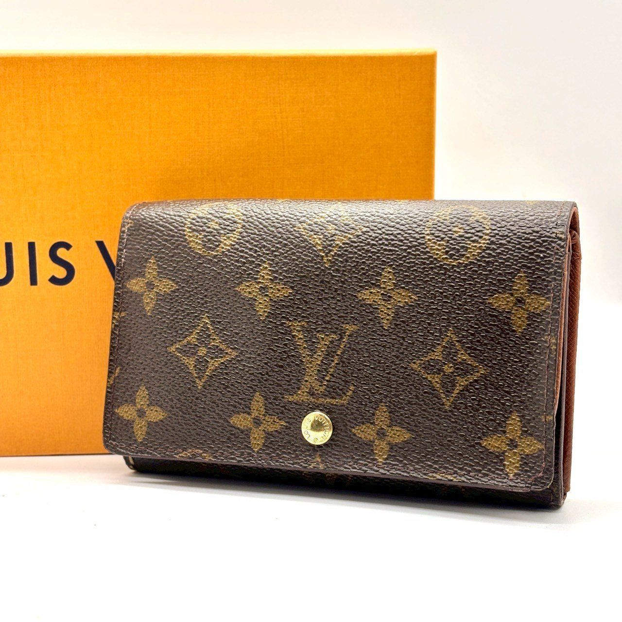 Brown Louis Vuitton monogram two-fold wallet (ポルトモネビエ トレゾール M61730) shown closed with an orange Louis Vuitton box behind it.