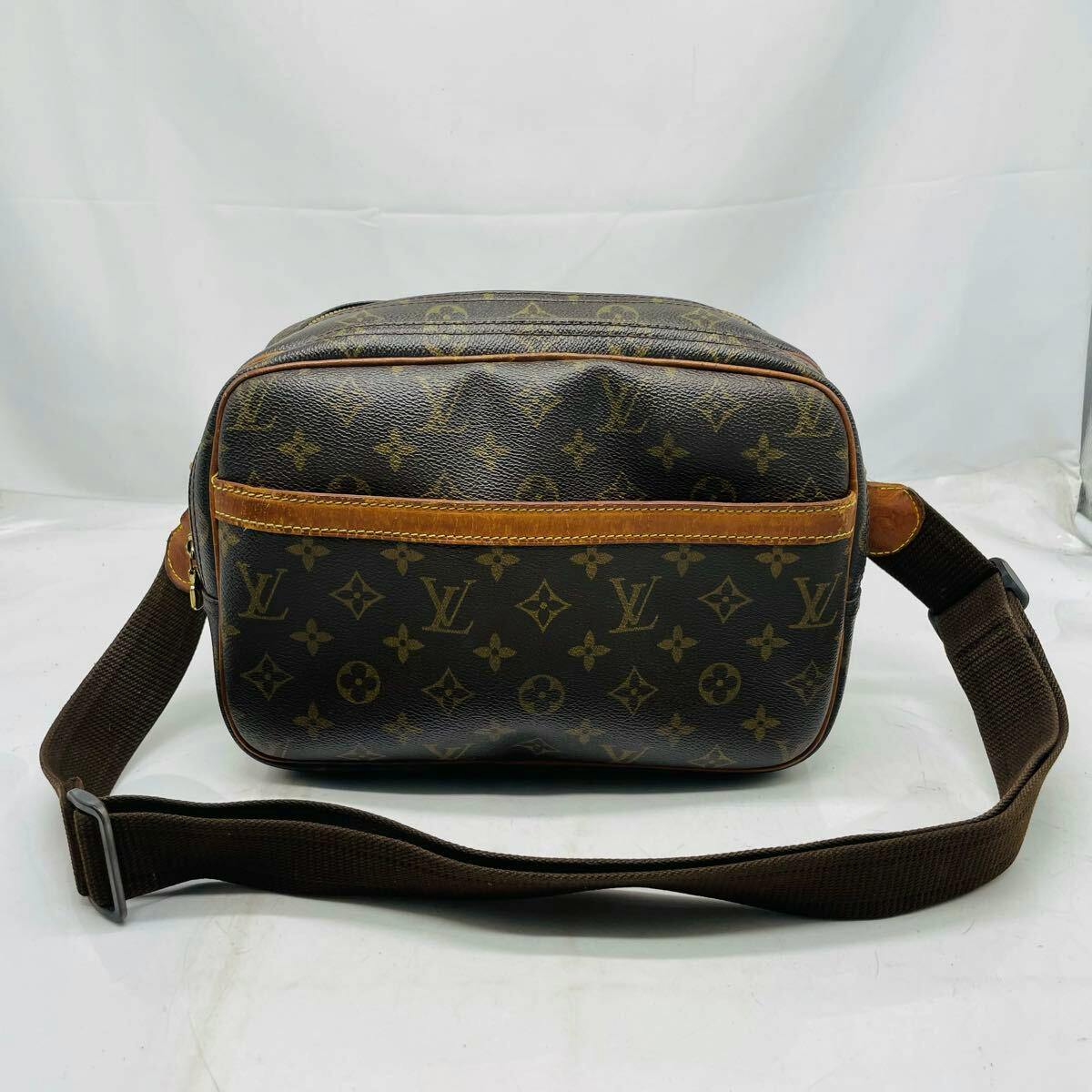 Front view of a Louis Vuitton Monogram Reporter PM canvas shoulder bag with monogram print and brown adjustable strap on a white background.