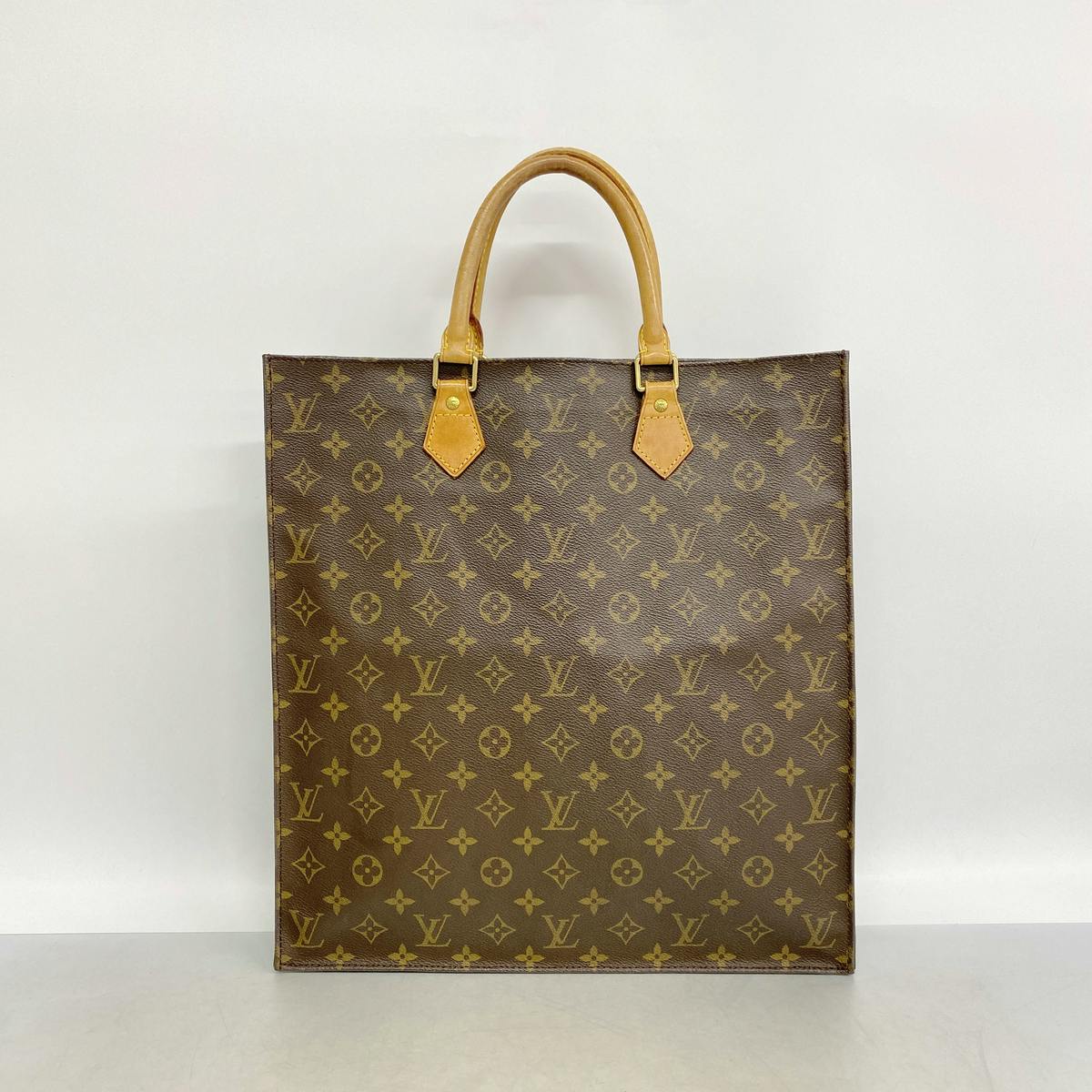 Front view of a Louis Vuitton Monogram Sac Plat (M51140) brown canvas tote bag with leather handles.