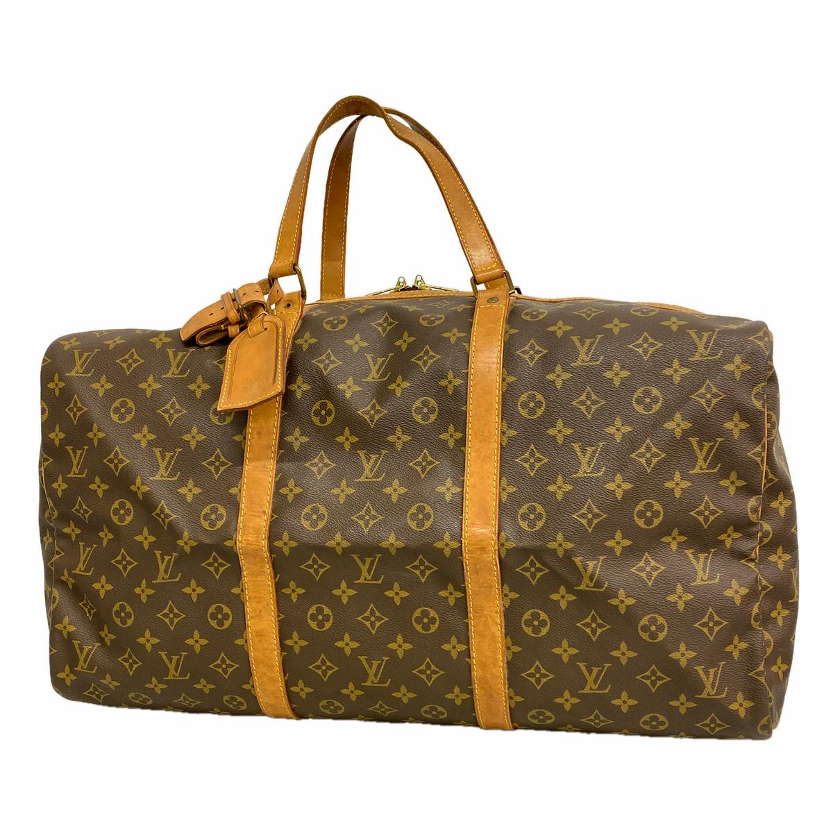 Louis Vuitton Monogram Sac Souple 55 (M41622) brown monogram canvas duffle bag with tan leather handles and straps on a white background.