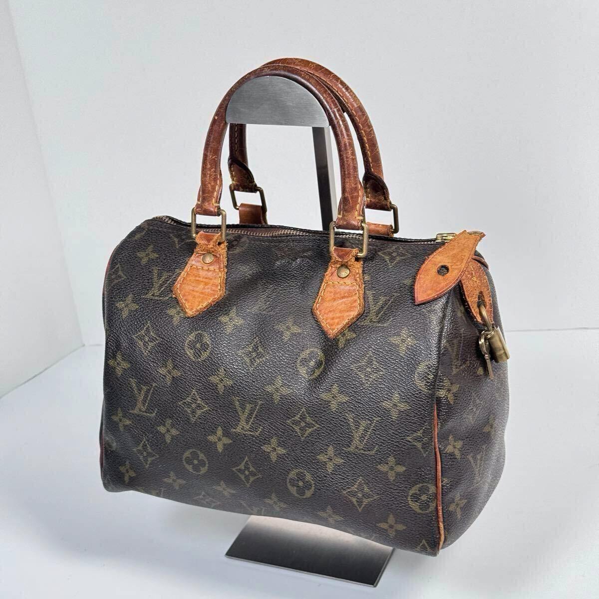 Monogram Louis Vuitton Speedy25 mini boston handbag with leather handles and padlock displayed on a stand.