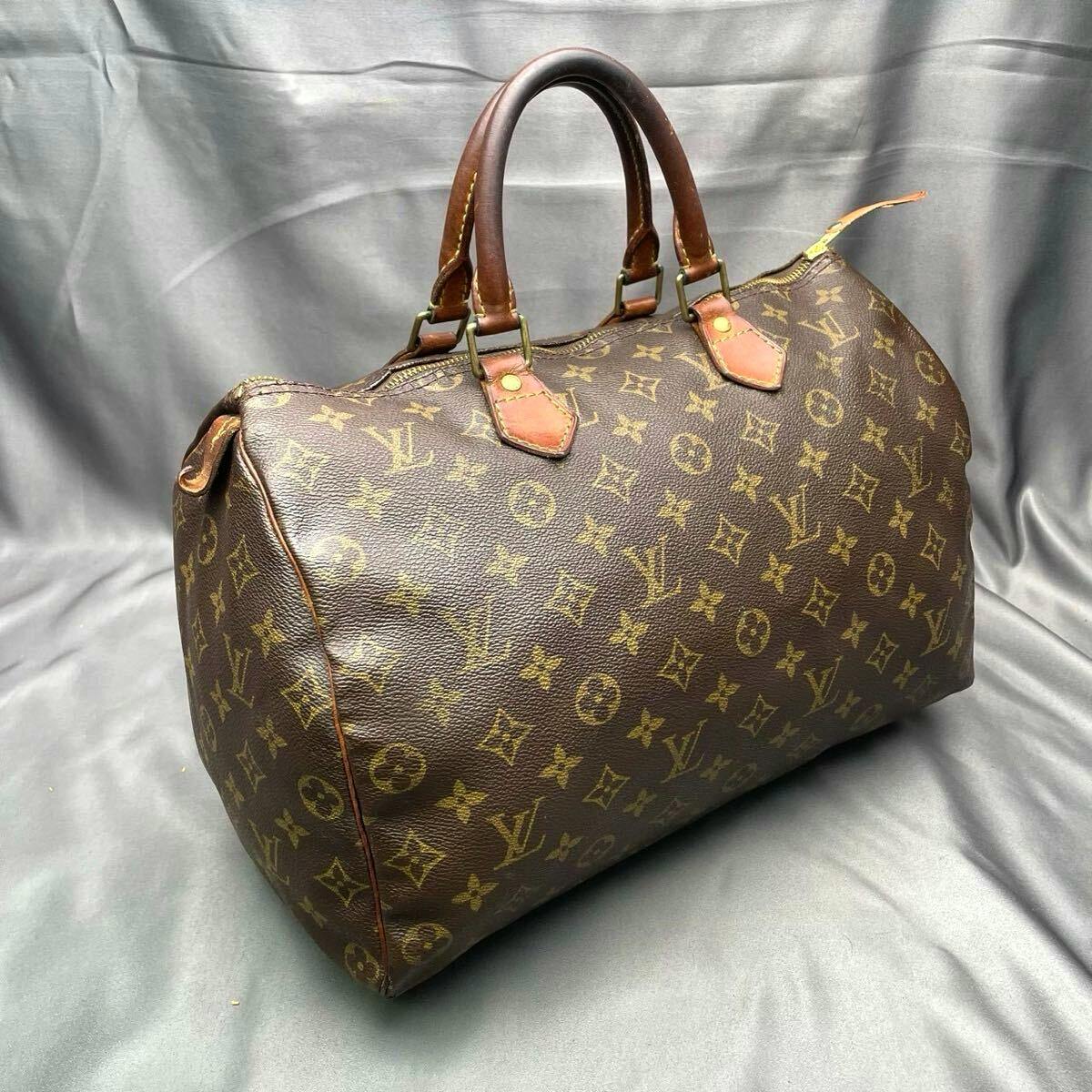 Louis Vuitton Monogram Speedy 30 handbag on a gray background showing the front and side with leather handles.