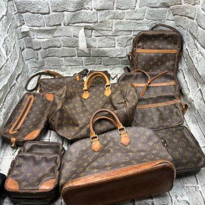 Multiple Louis Vuitton monogram bags (handbags and shoulder bags) arranged on a textured backdrop.