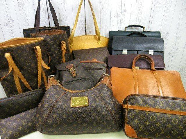 Group of Louis Vuitton bags and briefcases of various styles arranged on a wooden backdrop.