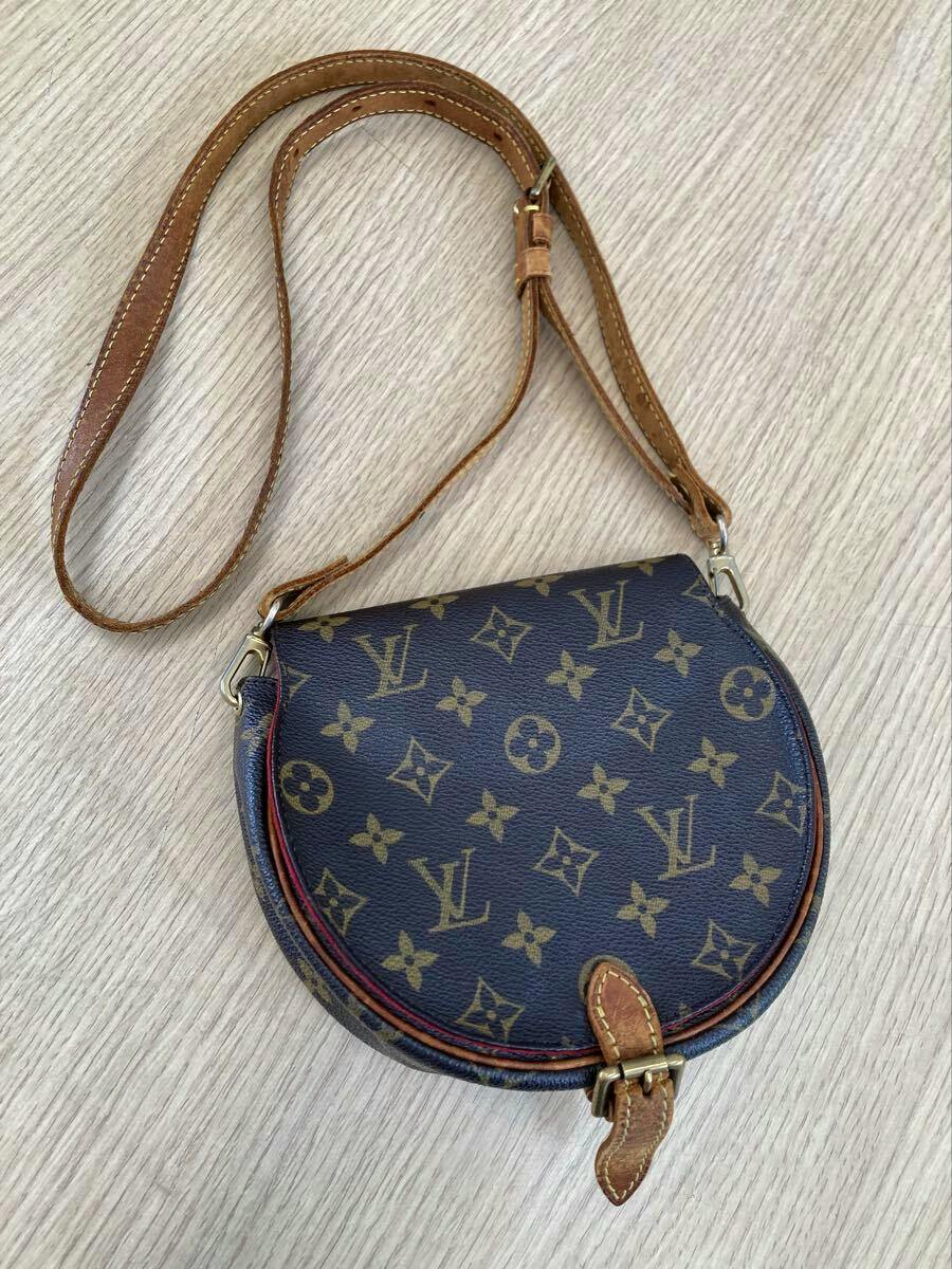 Louis Vuitton monogram canvas shoulder bag with leather strap laid flat on a wooden surface.