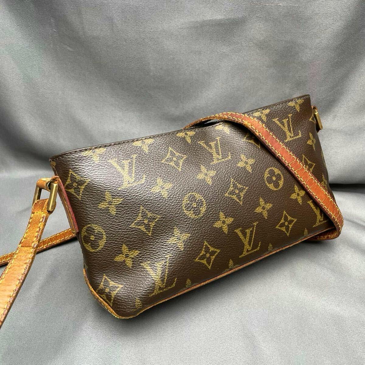 Brown Louis Vuitton monogram shoulder bag with leather strap on a gray background.