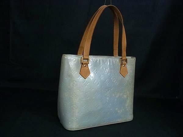 Light-blue Louis Vuitton Monogram Vernis Houston tote handbag with brown leather shoulder straps on a black background.