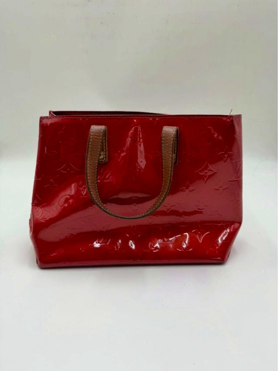 Red LOUIS VUITTON Monogram Vernis Reade PM handbag with brown handles shown front-on against a white background.