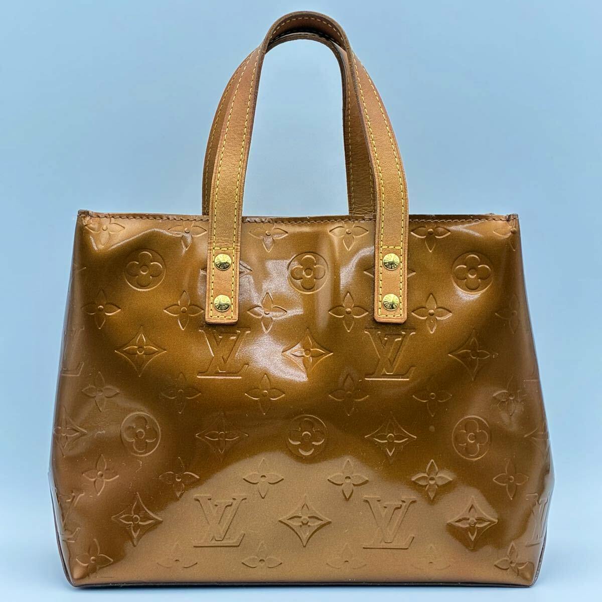 Front view of a bronze Louis Vuitton Monogram Vernis Lead PM tote handbag showing embossed monogram pattern and top handles.