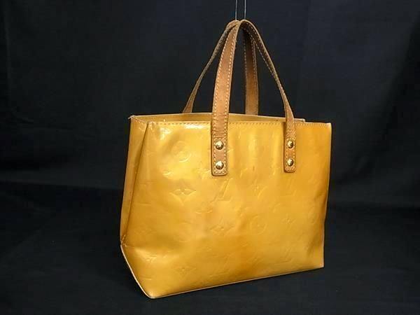 Beige Louis Vuitton Monogram Vernis Lead PM tote handbag with short handles on a black background.