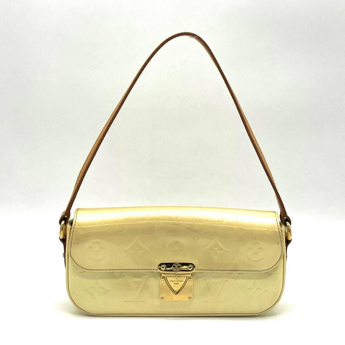 Front view of a Louis Vuitton monogram Vernis one-shoulder accessory pouch handbag on a white background, showing the flap and gold clasp.