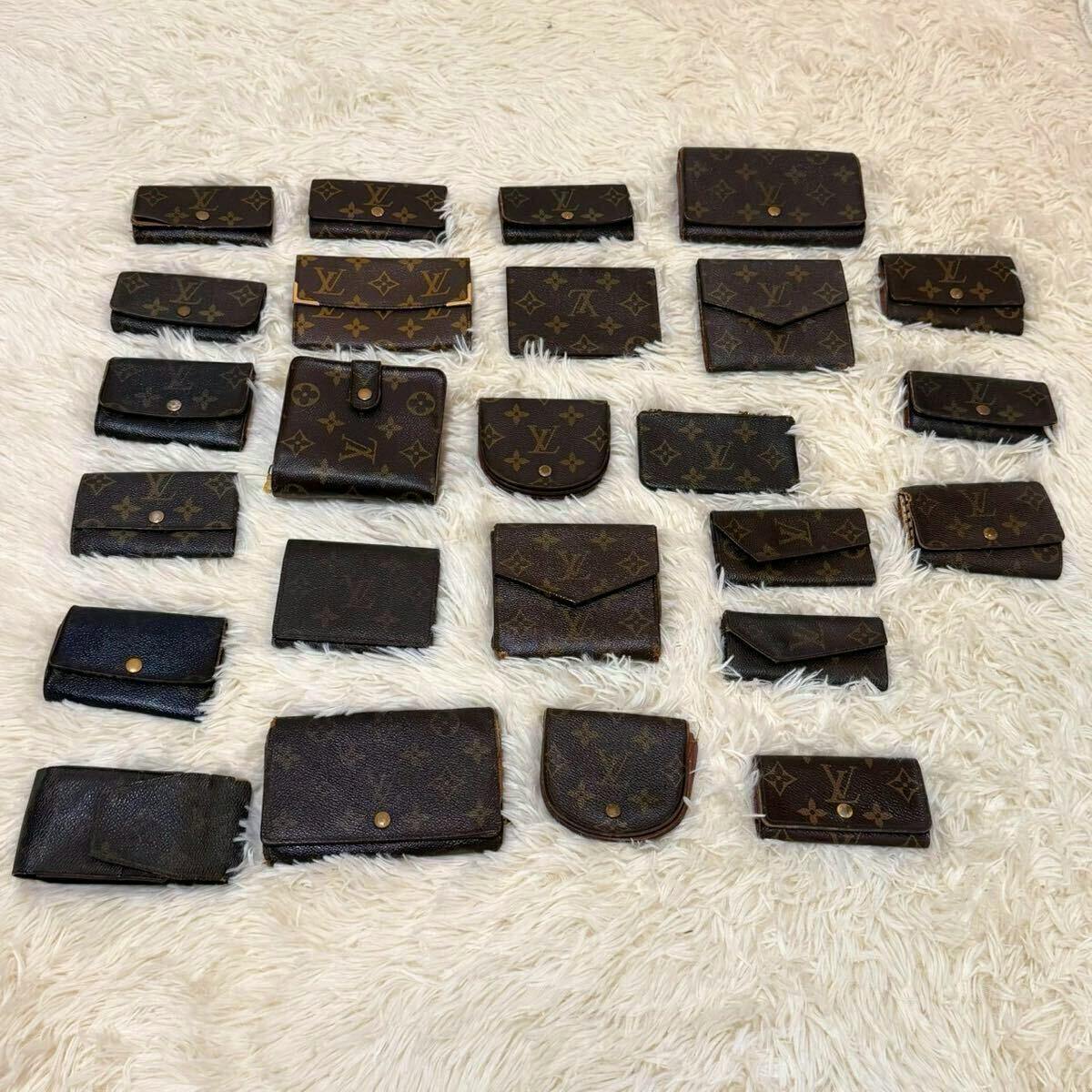 Multiple Louis Vuitton monogram wallets and key cases arranged on a white rug.