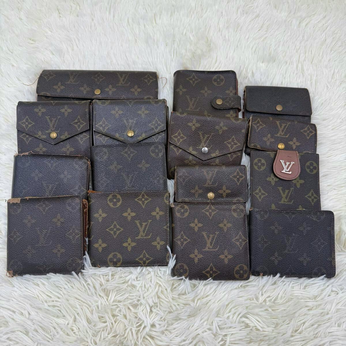 Fifteen Louis Vuitton monogram wallets and small leather goods arranged on a white fur rug.