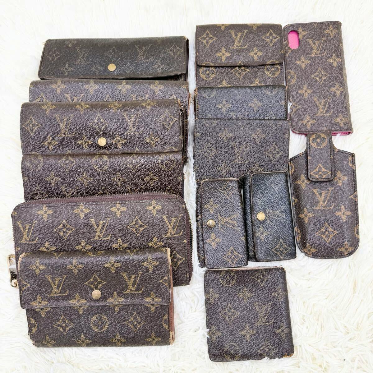 Multiple Louis Vuitton monogram wallets, key cases, and small accessories arranged on a white surface.