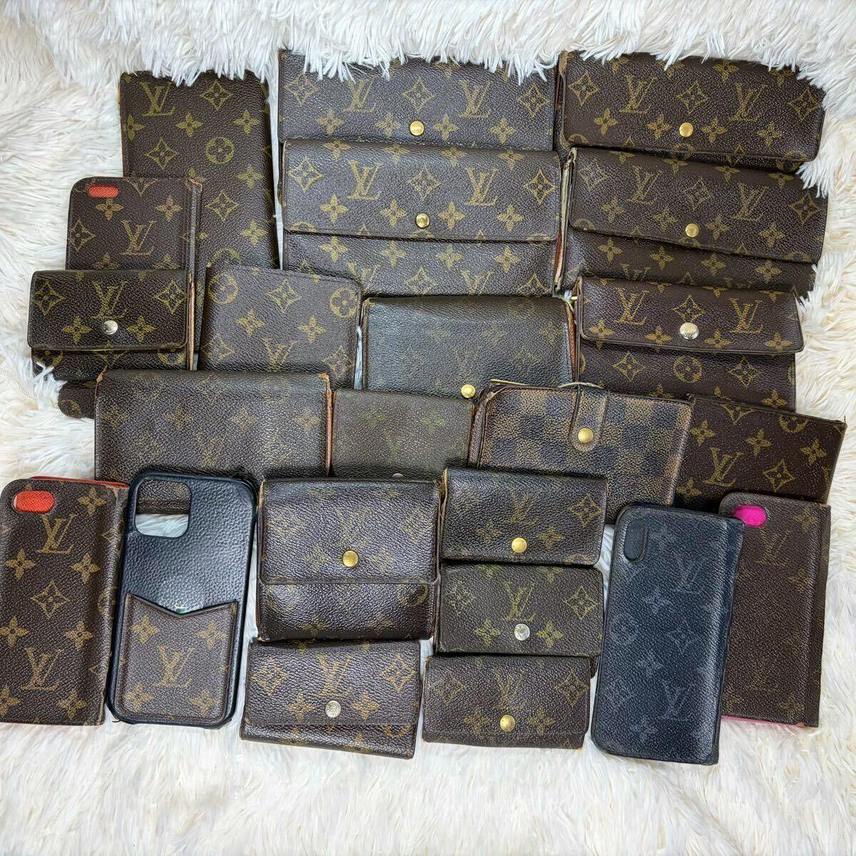 Multiple Louis Vuitton monogram wallets and small leather cases arranged on a white fur surface.